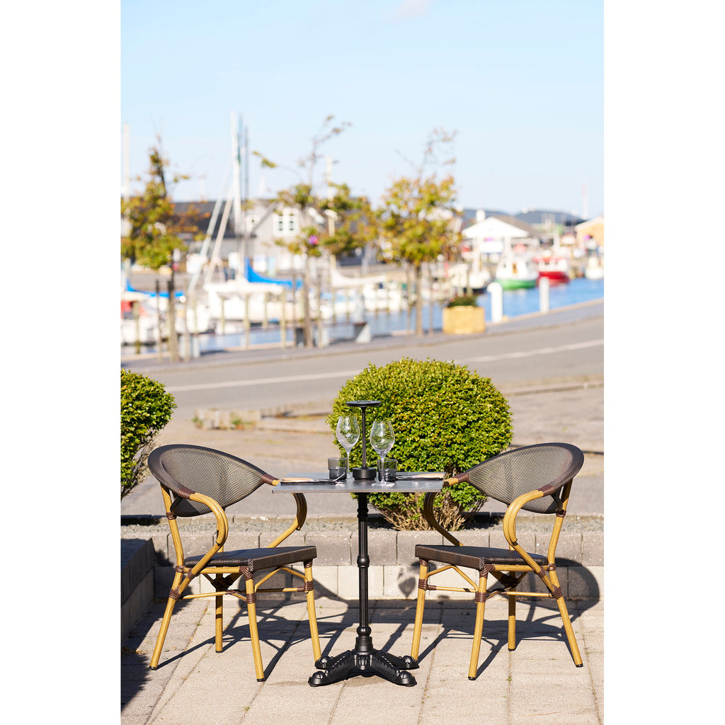 Table bistrot marbre noir fonte ciselée en situation terrasse bord de mer avec chaises bistrot