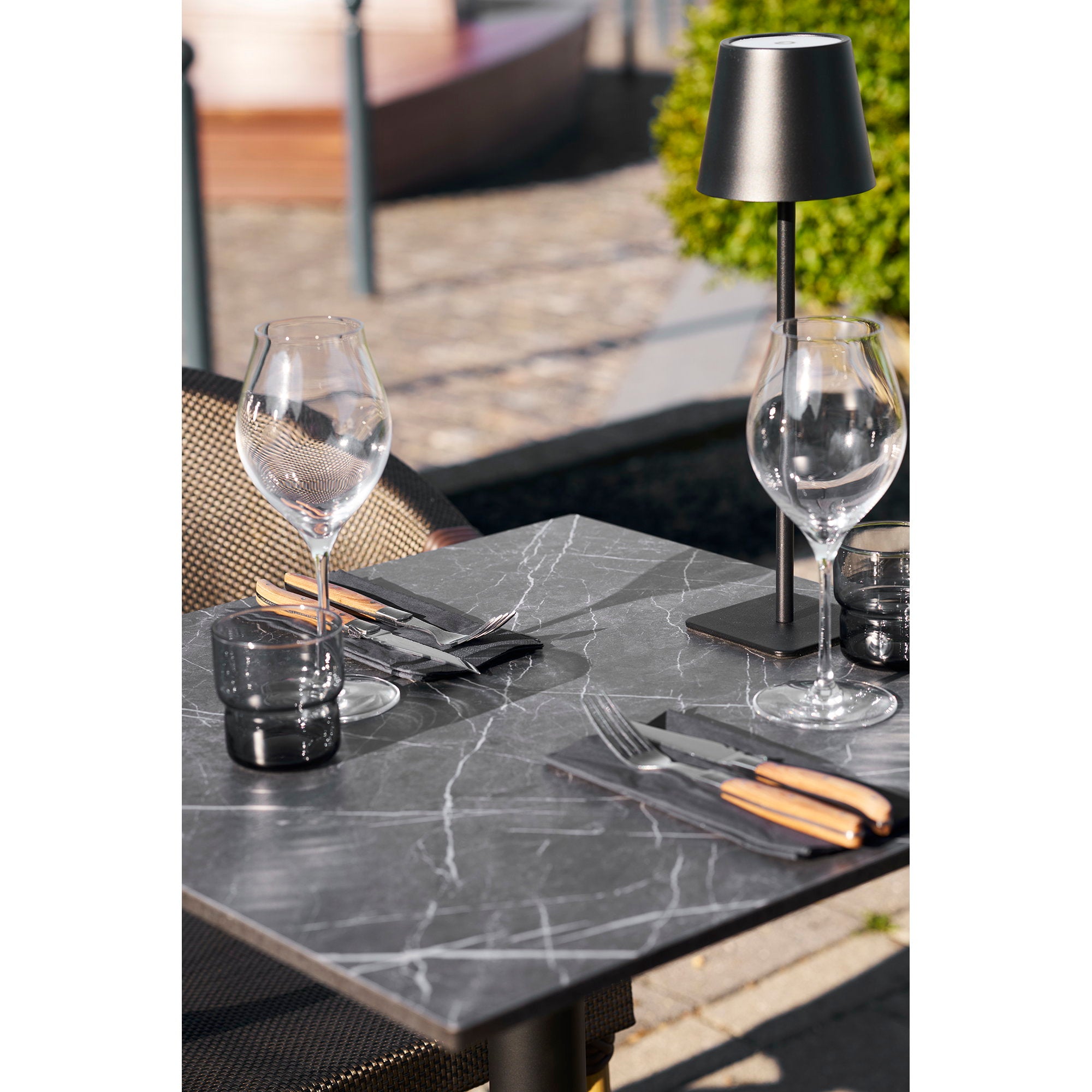 Gros plan plateau effet marbre noir veinures blanches dressé verres couverts bois terrasse