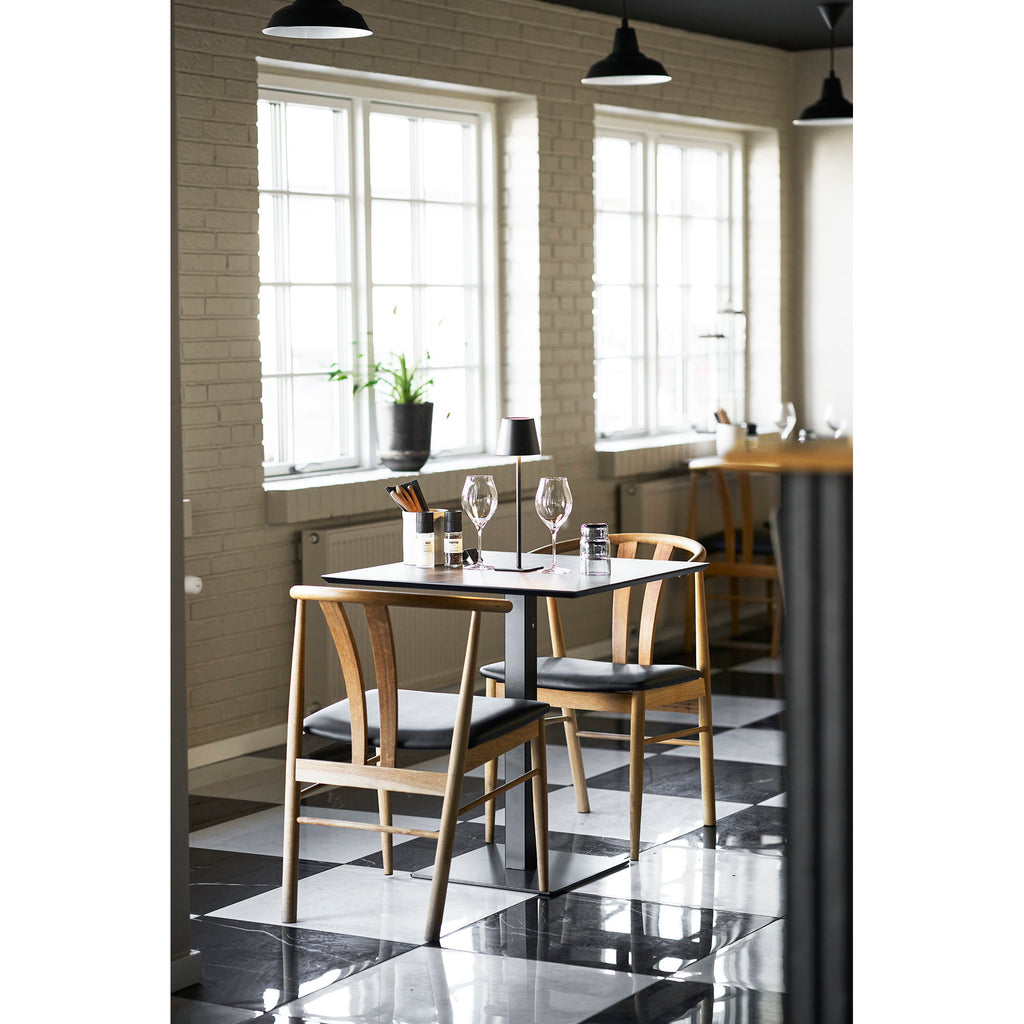 Table café Fano effet pierre anthracite en situation bistrot lumineux avec chaises bois