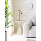 Table d'appoint Annecy portant une lampe à poser en métal argenté à côté d'un canapé en tissu gris clair