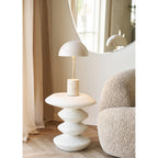 Table d'appoint Blackburn portant une lampe à pied de travertin à côté d'un fauteuil bouclé