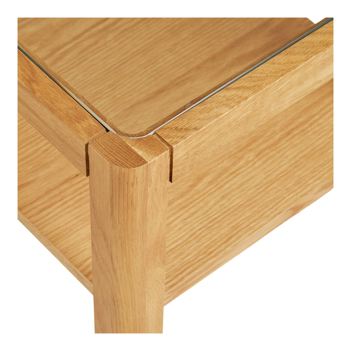 Détail d'un angle de la table Lourmarin où le haut du pied affleure l'encadrement et le verre