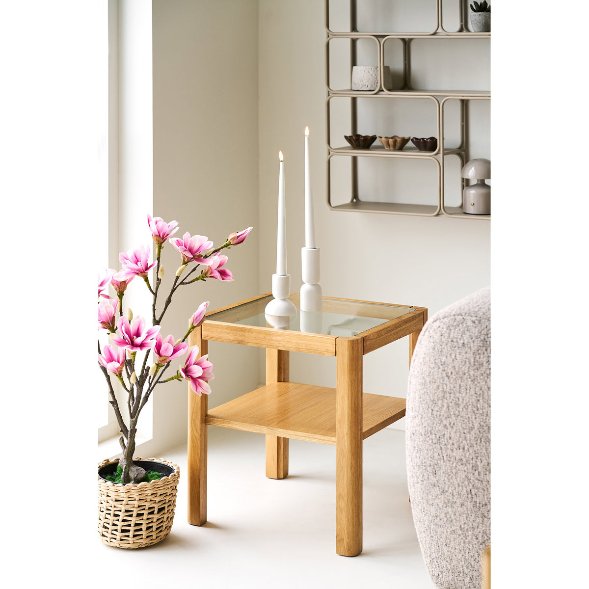 Table d'appoint Lourmarin près d'un canapé bouclé avec deux bougeoirs blancs sur le plateau en verre