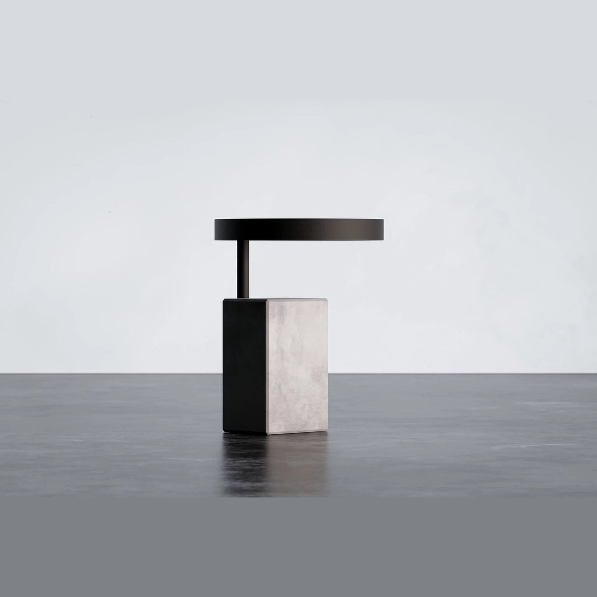 Table d'appoint Twist sur un sol sombre avec sa base en béton gris à flanc noir