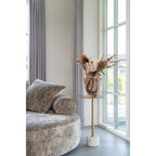 Table d'appoint Lecco 41 cm portant un vase fleuri près d'un canapé rond en tissu gris et d'une fenêtre