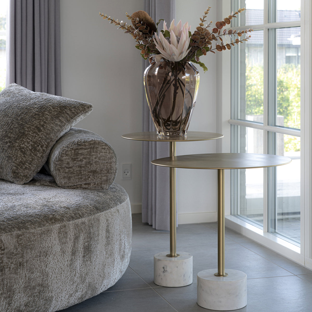 Tables d'appoint Lecco 41 cm et 51 cm aux plateaux étagés près d'un canapé rond en tissu gris devant une fenêtre