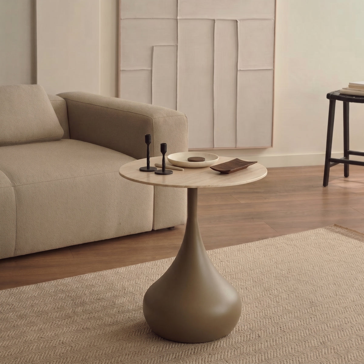 Table d'appoint Pienza devant un canapé beige, sur un tapis à chevrons, avec bougeoirs noirs et coupelle sur le plateau