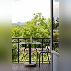 Table de bistro Donut rectangulaire sur un balcon ouvert sur les arbres avec carafe verres et planche en bois