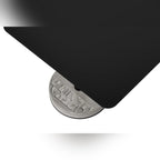 Vue plongeante sur l'angle du plateau en aluminium noir et le motif en relief du socle en béton de la table Donut