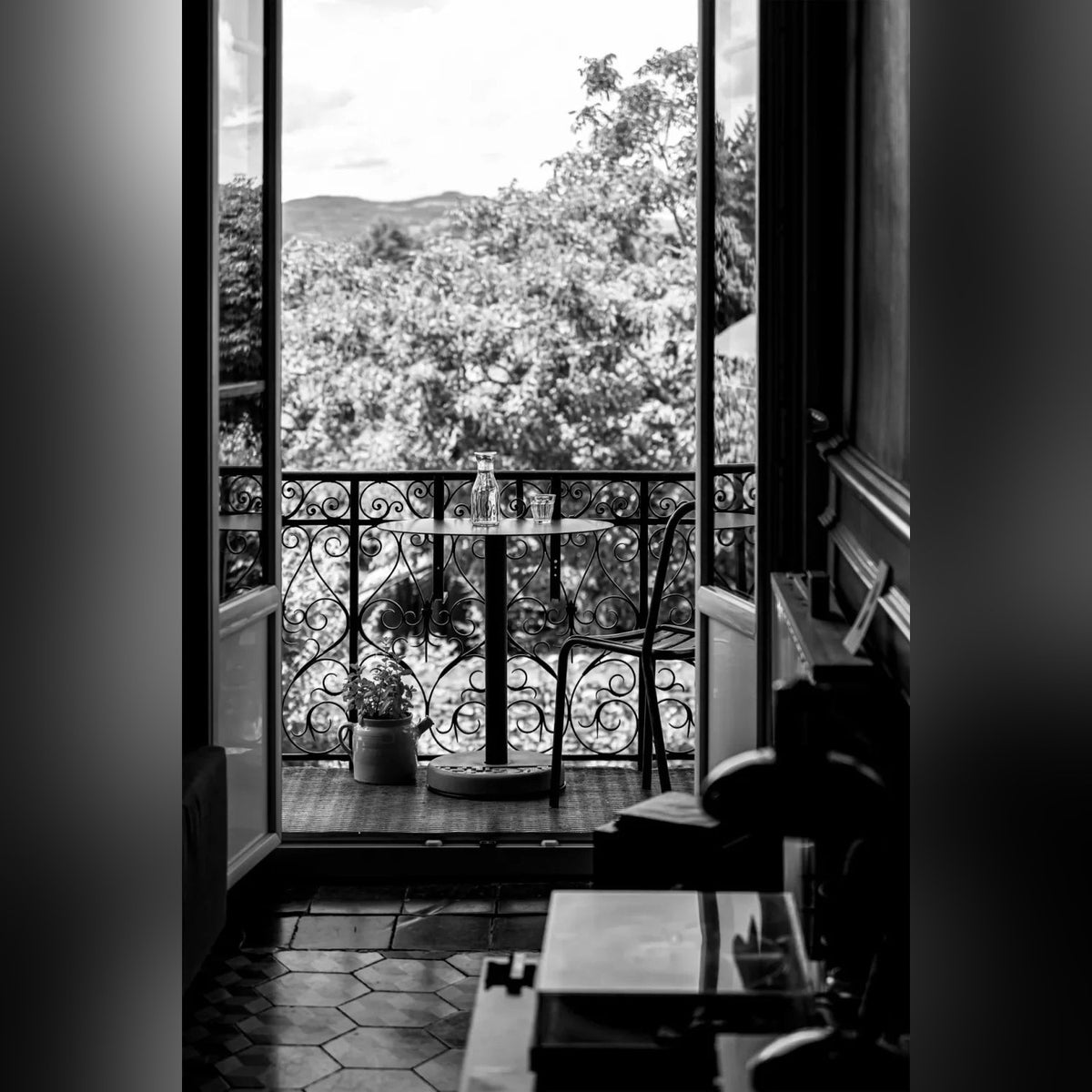 Table de bistro Donut sur un balcon à garde-corps en fer forgé avec une carafe et une chaise