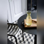Table de bistro Donut avec une carafe sur une planche en bois à côté d'une chaise en métal