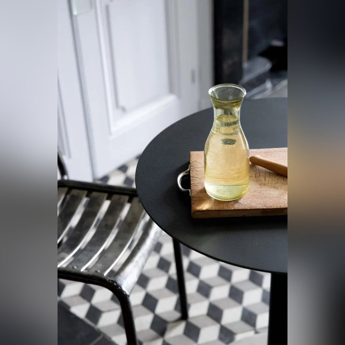 Table de bistro Donut avec une carafe sur une planche en bois à côté d'une chaise en métal