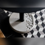 Gros plan sur le motif géométrique en relief du socle en béton de la table Donut