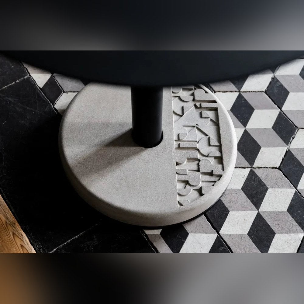 Gros plan sur le motif géométrique en relief du socle en béton de la table Donut