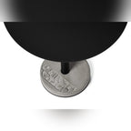 Vue plongeante sur le plateau rond noir et le socle en béton à motif géométrique de la table Donut