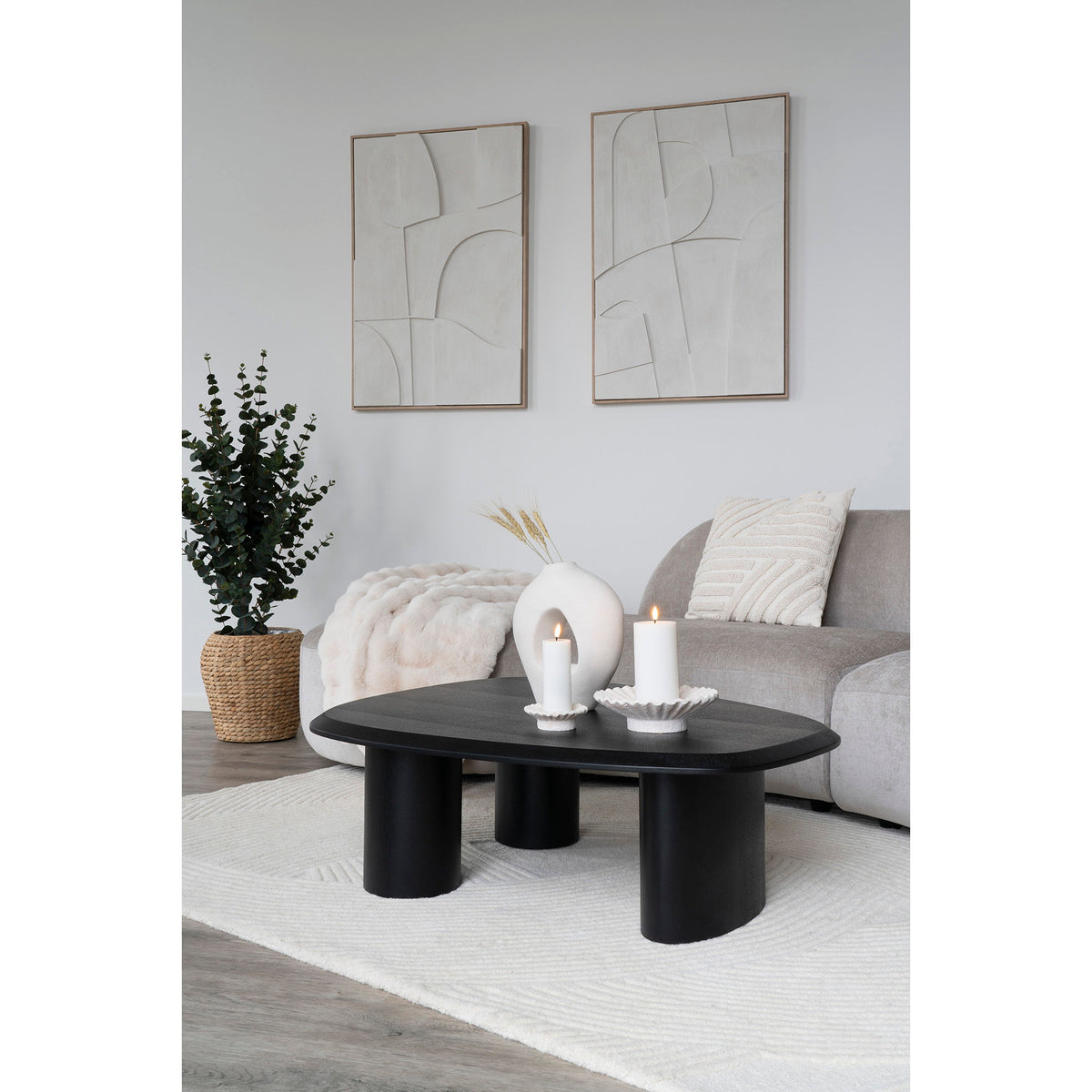Tableau Madeline blanc accroché à côté d'une autre composition de la série au-dessus d'un canapé gris et d'une table basse noire