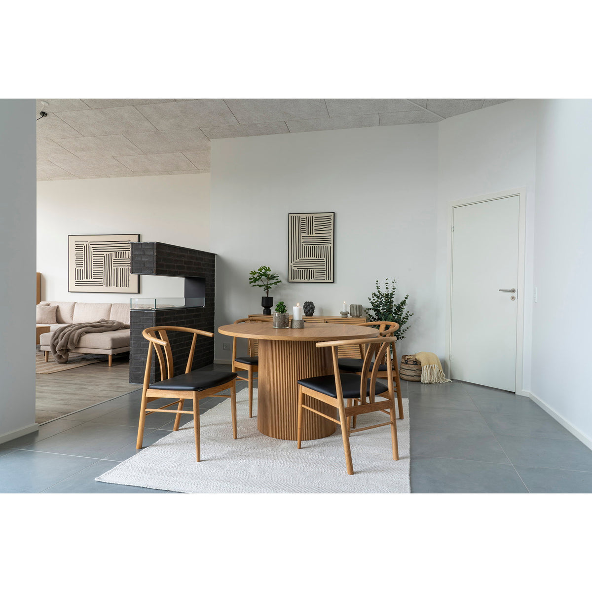 Salle à manger ouverte avec le tableau Lipari stries croisées au mur et un autre tableau graphique derrière le canapé
