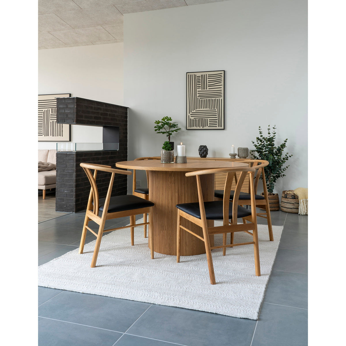 Tableau Lipari stries croisées au-dessus d'une table ronde en bois entourée de chaises en chêne avec un autre tableau graphique au fond
