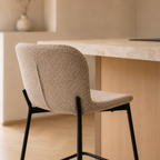 Gros plan sur le dossier d'un tabouret de bar en tissu bouclé beige texturé et son piètement en métal noir mat