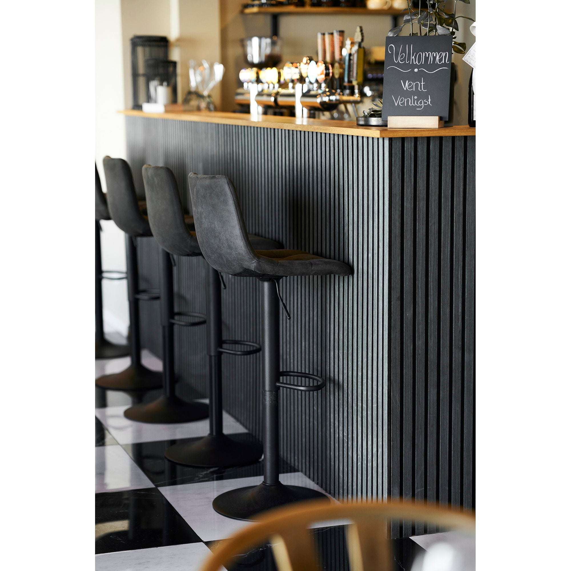 Tabourets de bar réglables Middelfart microfibre gris foncé alignés devant un comptoir de bar style restaurant