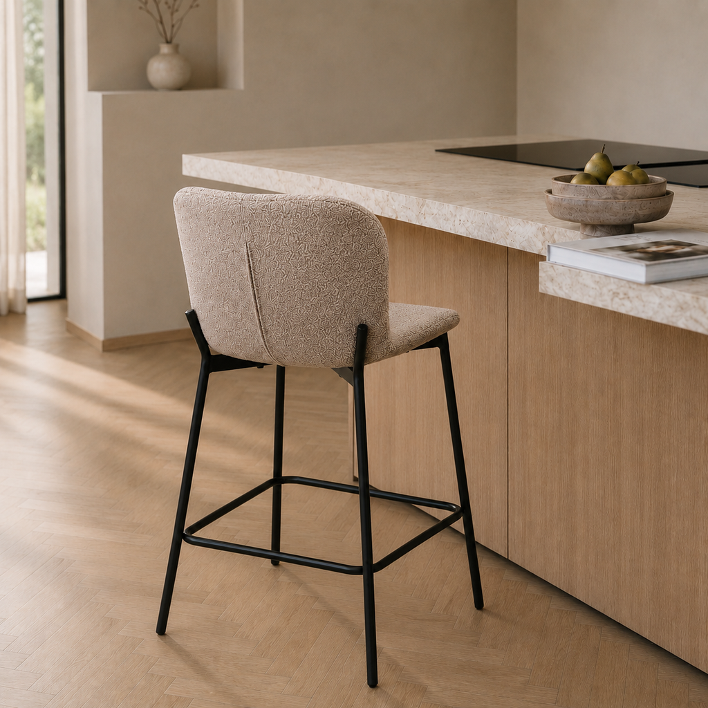 Tabouret de bar en tissu bouclé beige à piètement métal noir, installé de dos contre un îlot de cuisine en bois clair