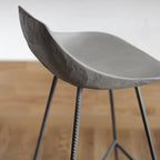 Coque en béton du tabouret de bar Hauteville en gros plan avec sa face extérieure texturée et ses pieds en fer à béton