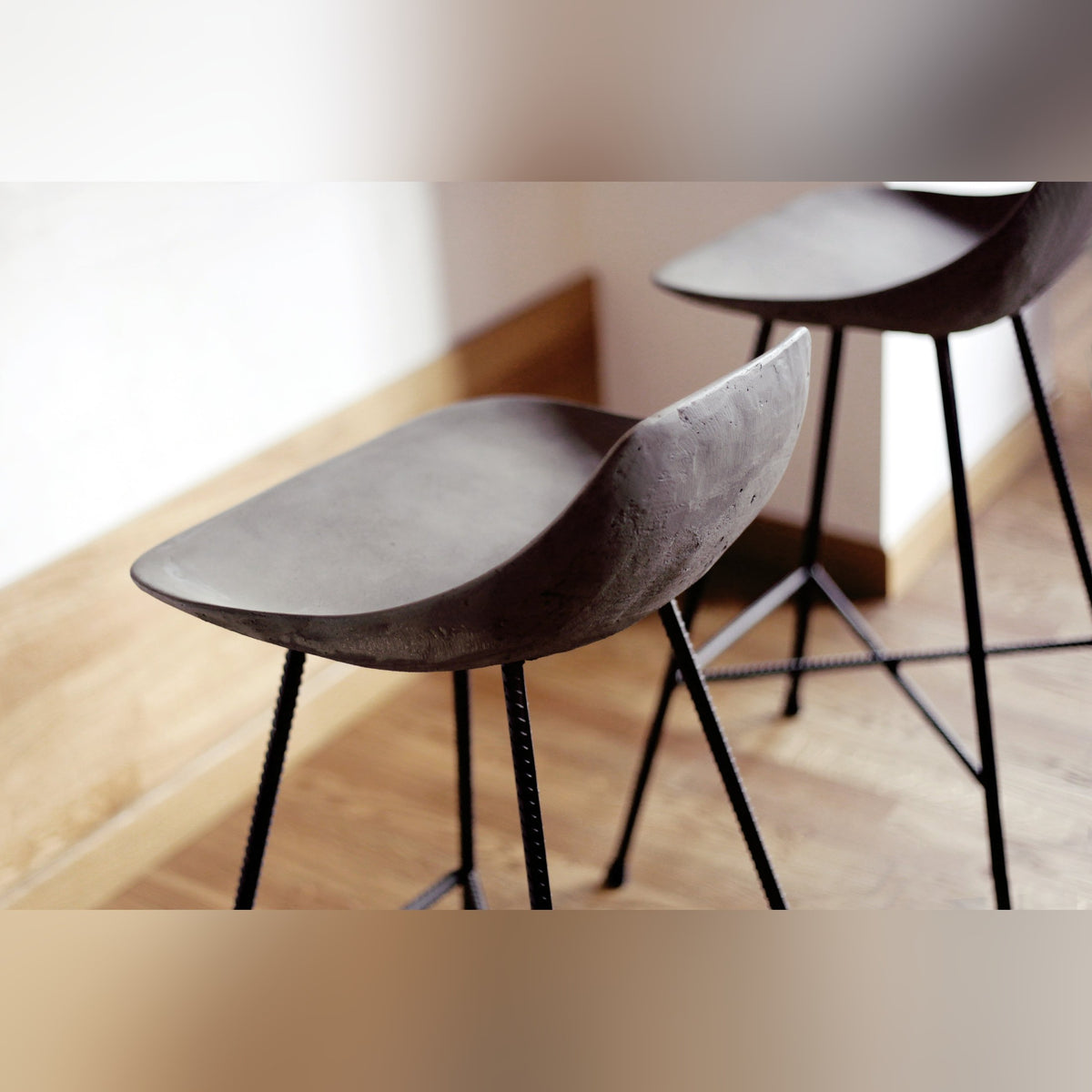 Coques en béton de deux tabourets de bar Hauteville vues de près au-dessus d'un parquet