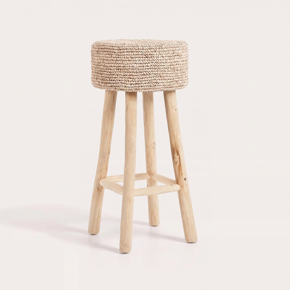 Tabouret de bar Raffia vu de trois quarts sur fond blanc, assise ronde en raphia tressé sur quatre pieds en teck