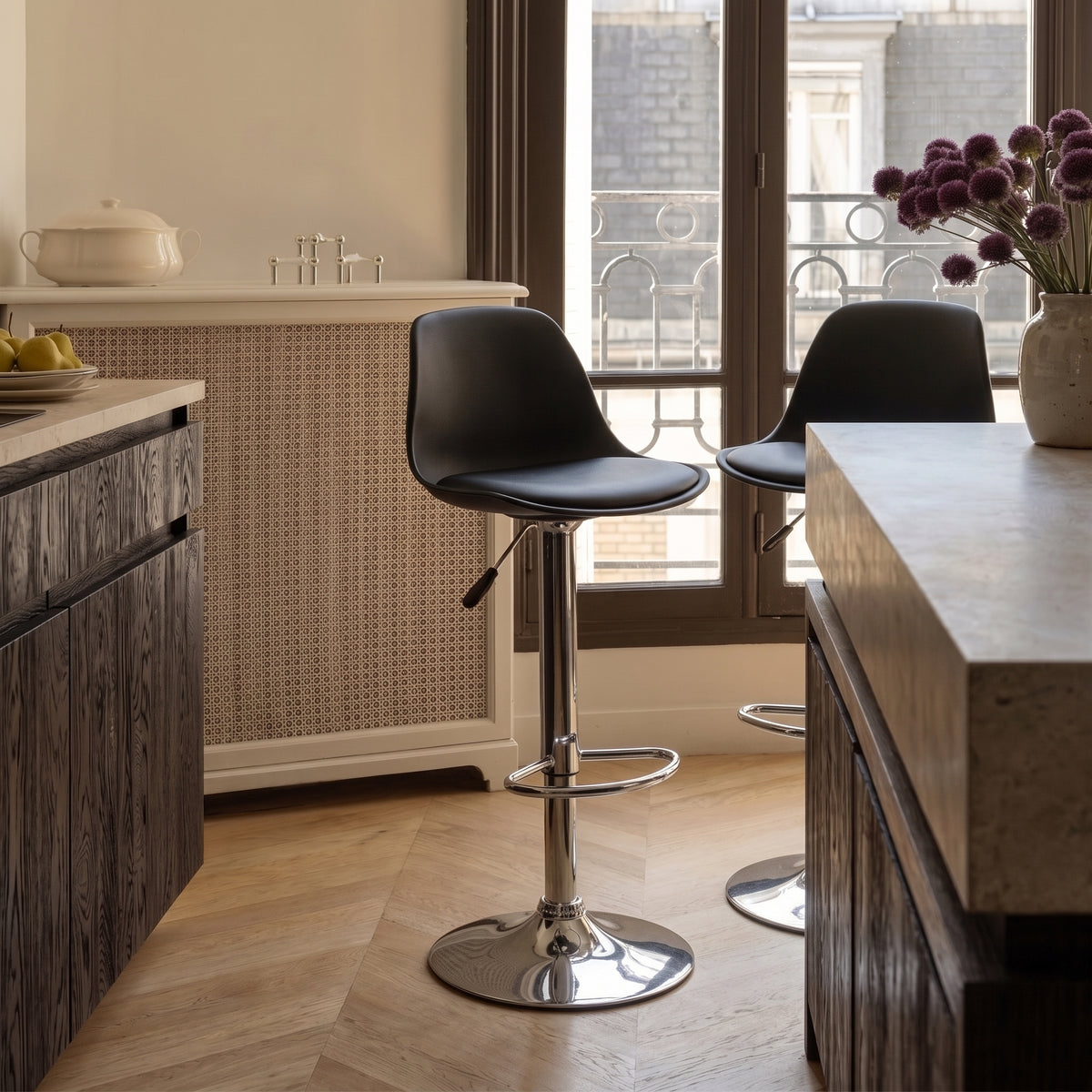 Deux tabourets de bar Trondheim en simili cuir noir devant un îlot en pierre, dans une cuisine au parquet en chevrons