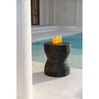 Tabouret Kotoran noir servant de petite table avec deux verres de jus d'orange au bord d'une piscine
