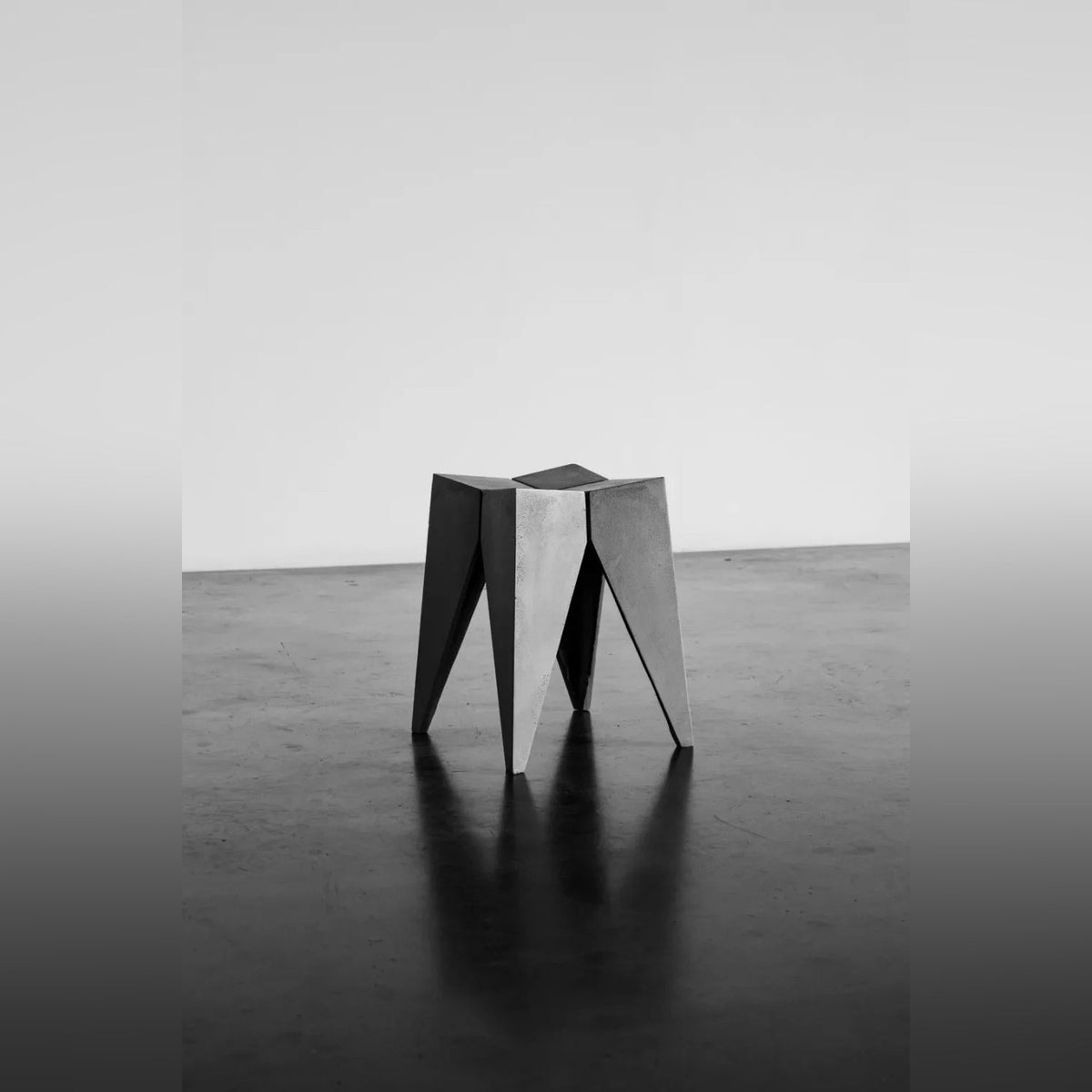 Tabouret Bridge en béton gris seul dans un espace d'atelier au sol brillant