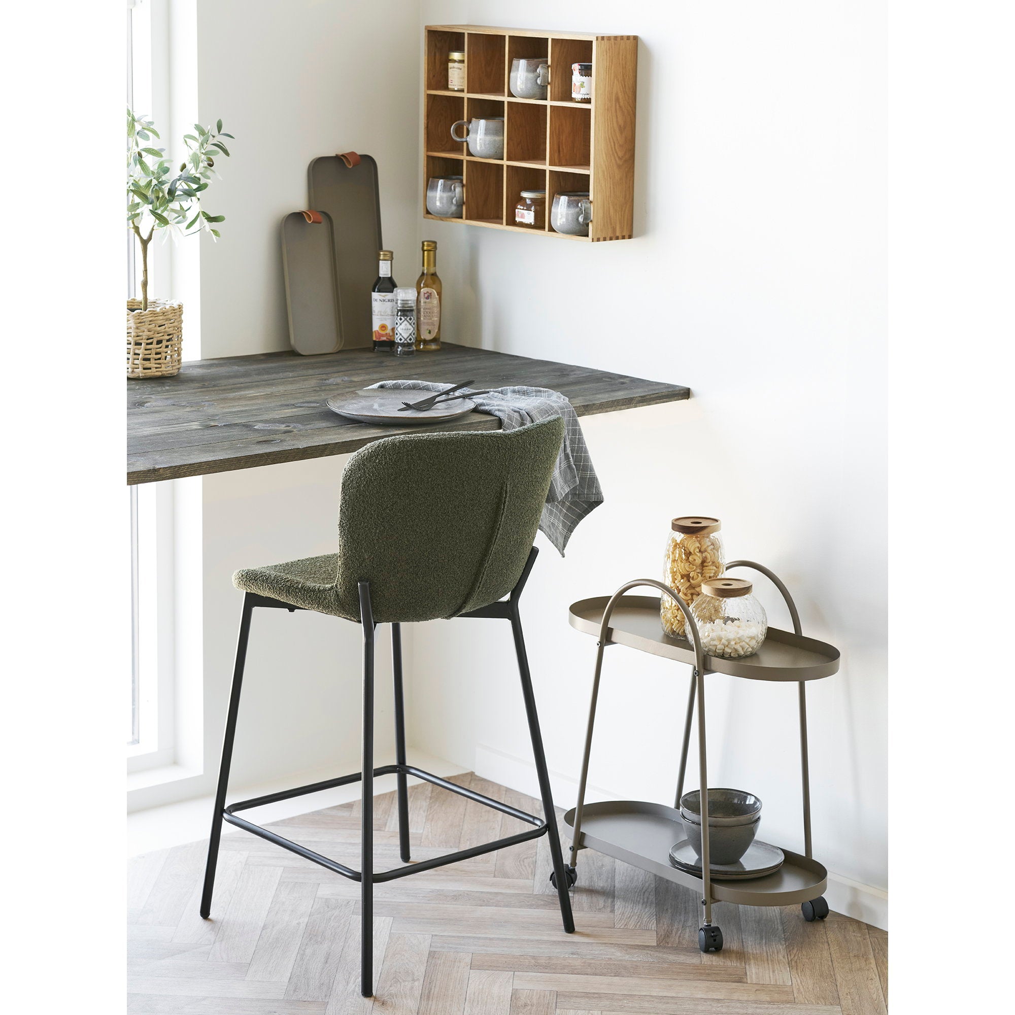 Tabouret bar Maceda bouclé vert kaki dans une cuisine contemporaine avec comptoir en bois grisé
