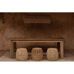 Tabouret Dannih à droite avec deux autres tabourets tressés sous une longue table en bois et une suspension en fibres