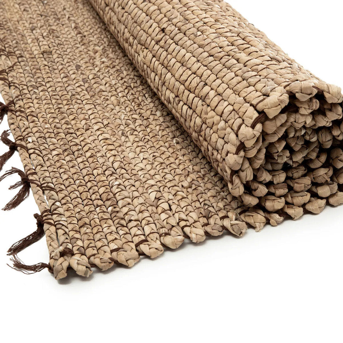 Détail du tissage en jacinthe d'eau tressée et fils de coton brun du tapis à demi déroulé