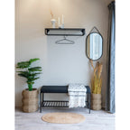 Tapis Bombay jute ovale naturel en entrée avec banc noir miroir et plantes vertes