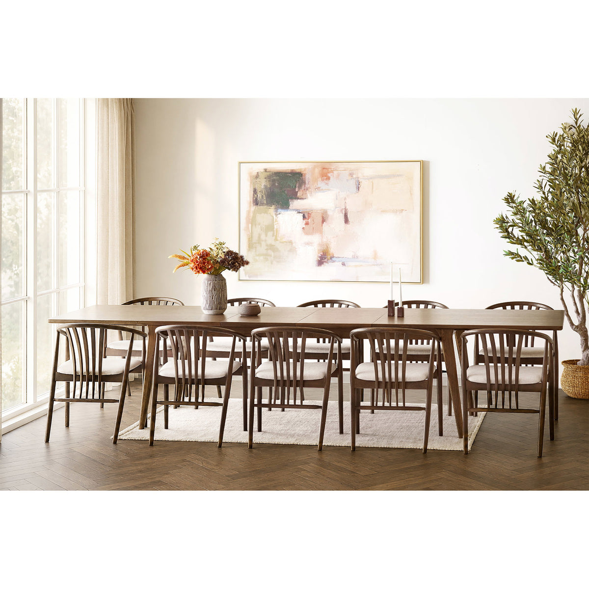 Tapis Gaya beige sous une longue table de salle à manger en bois entourée de chaises à barreaux