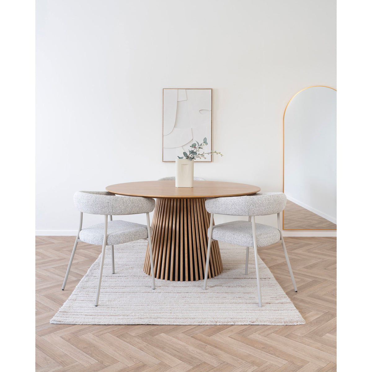 Tapis Mango 160 x 230 cm sous une table ronde en bois à pied à lamelles entourée de trois chaises