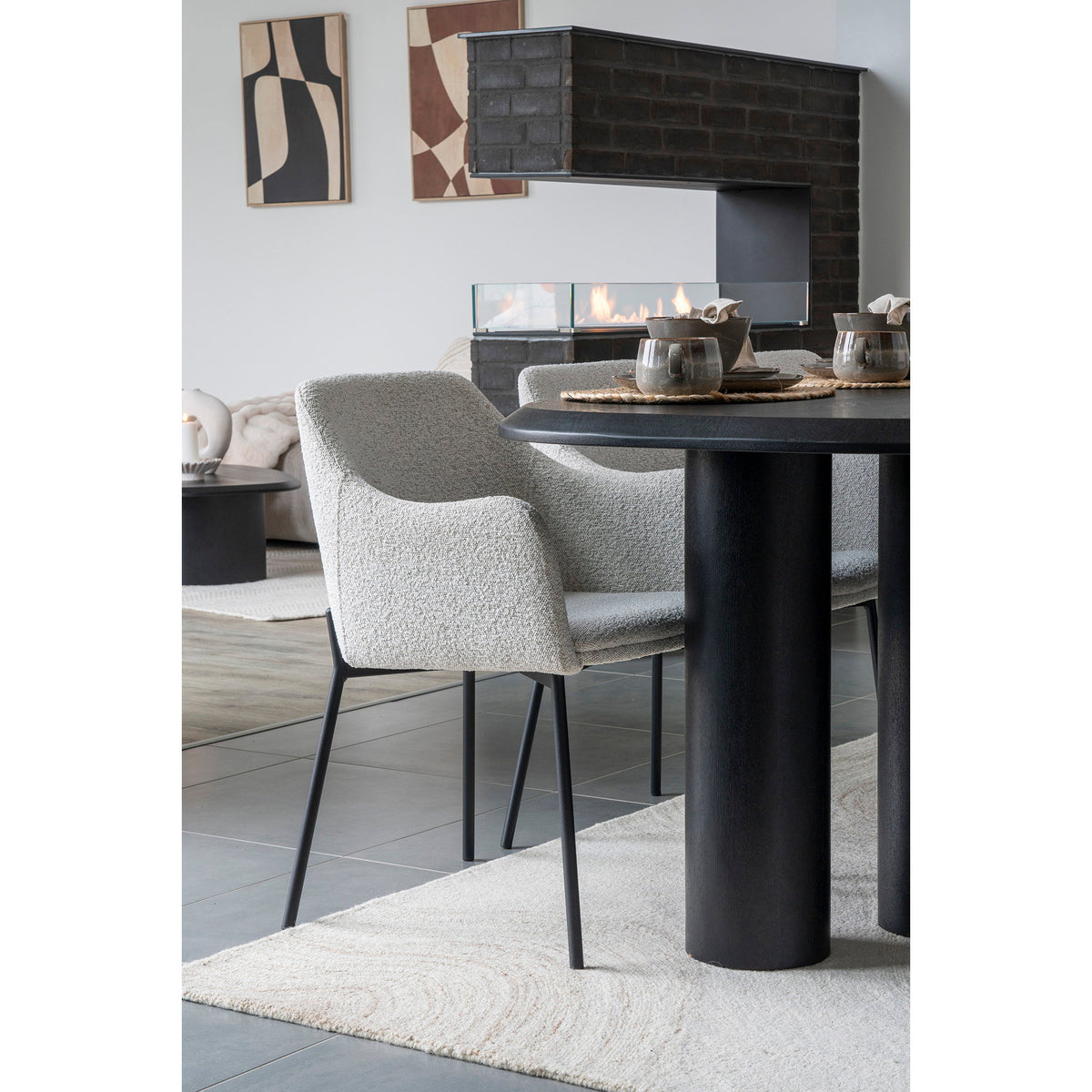 Angle du tapis Surat sous un fauteuil bouclé et une table noire devant une cheminée en briques