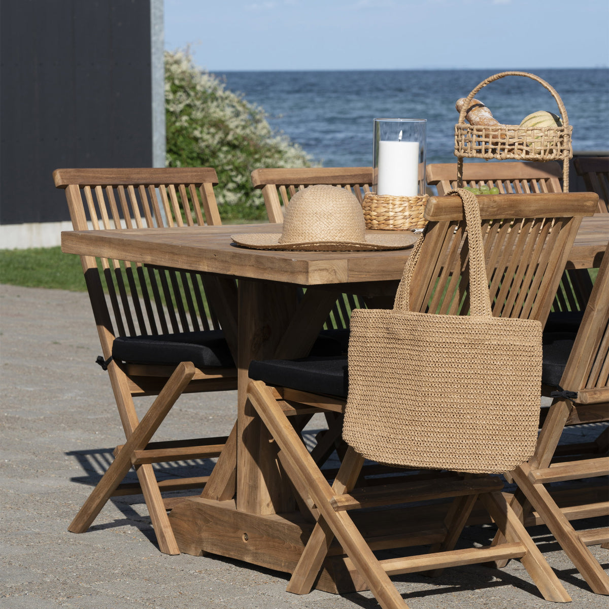 Tote bag Parade suspendu au dossier d'une chaise devant une table dressée face à la mer