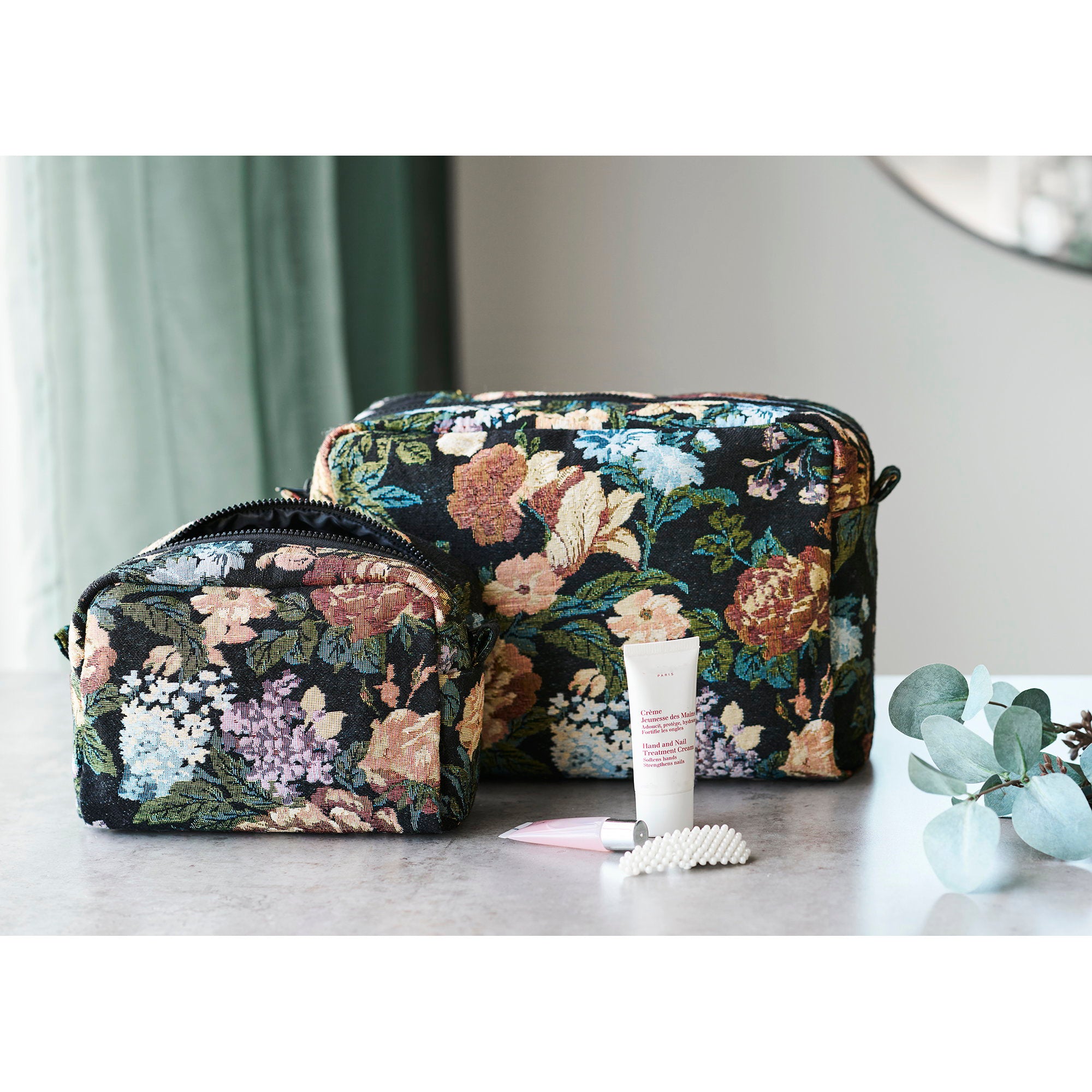 Set de 2 trousses de toilette Zoe jacquard fleuri noir posées sur marbre avec accessoires beauté