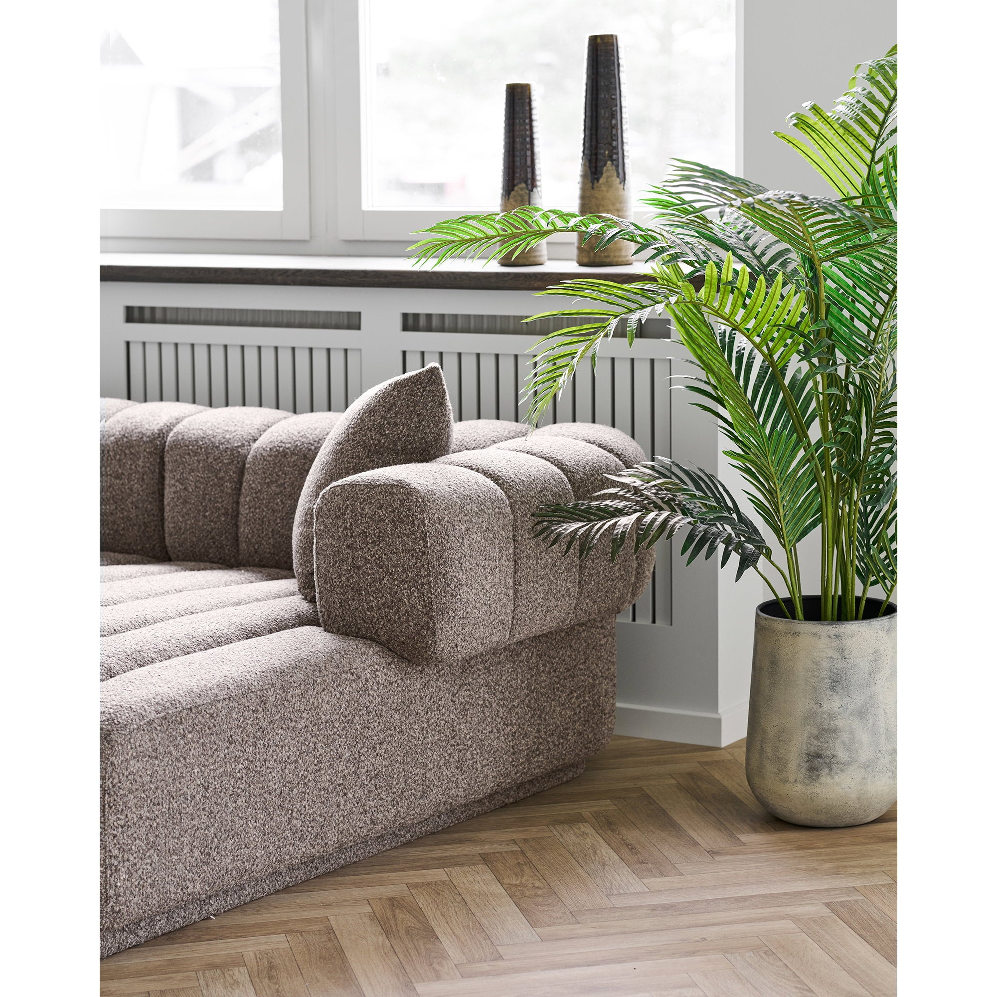 Vase céramique effilé brun tabac sur rebord fenêtre salon canapé angle bouclé et palmier