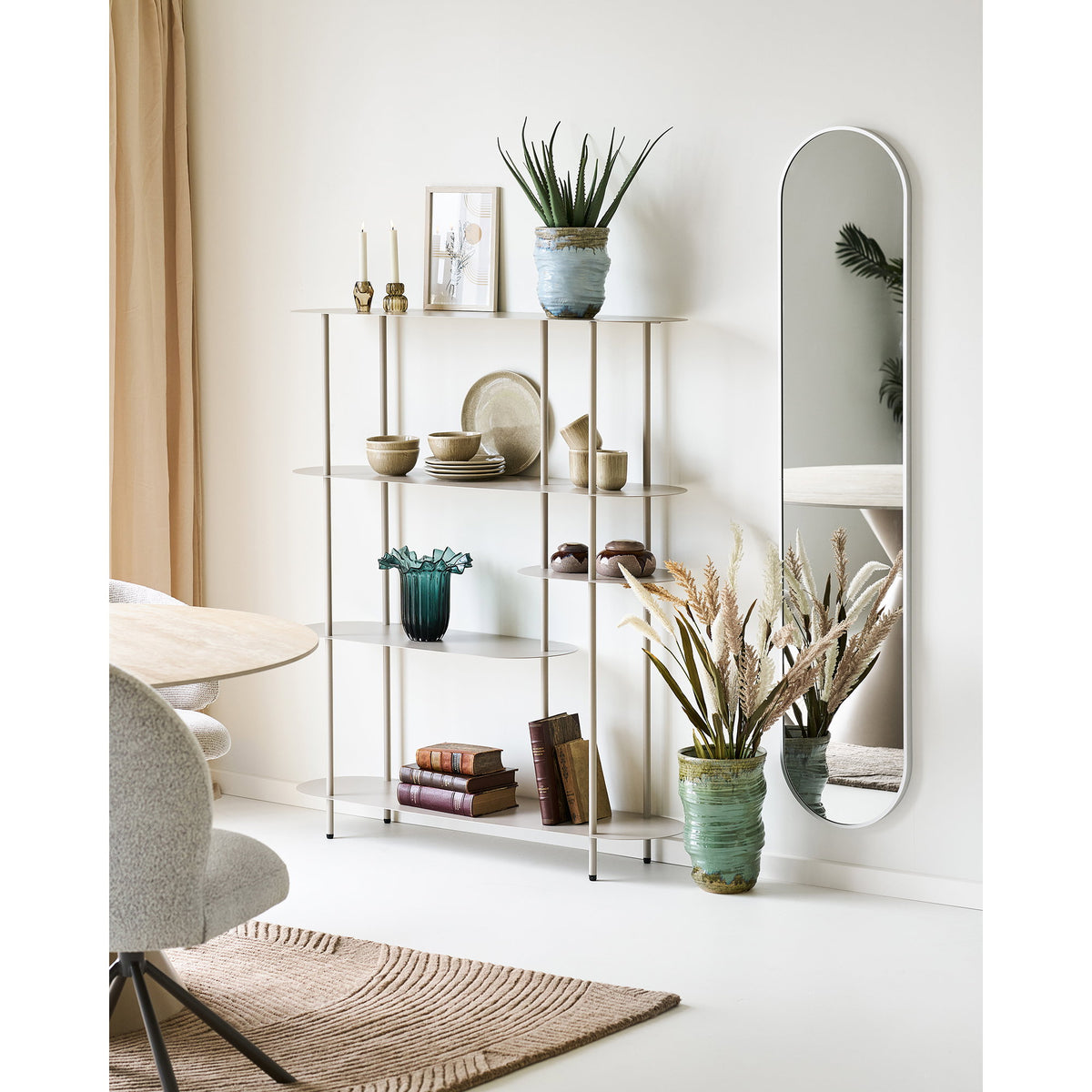 Vase céramique vert au sol avec graminées à côté d'une étagère métal beige garnie de vaisselle