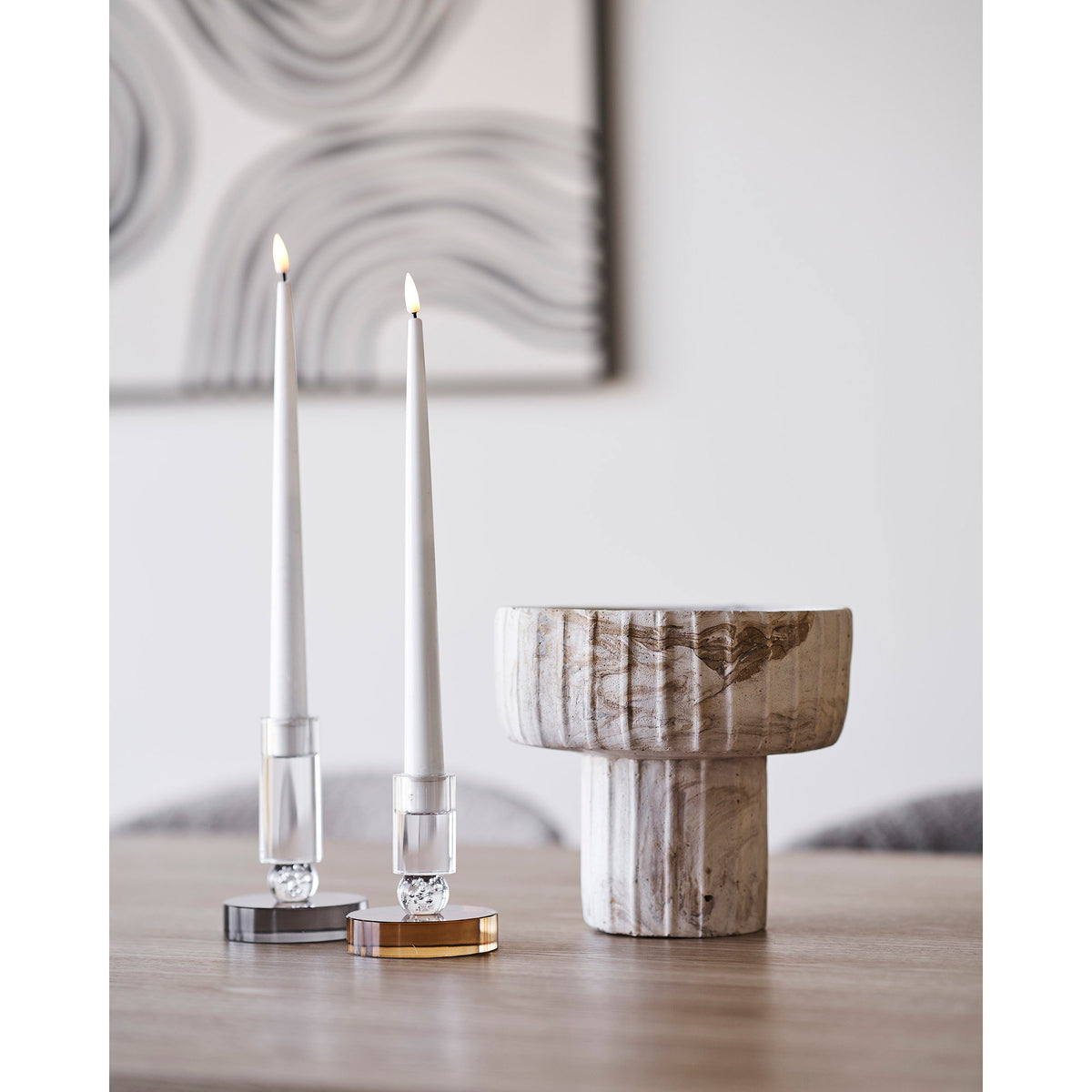 Vase coupe posé sur une table à côté de deux bougeoirs et de bougies allumées