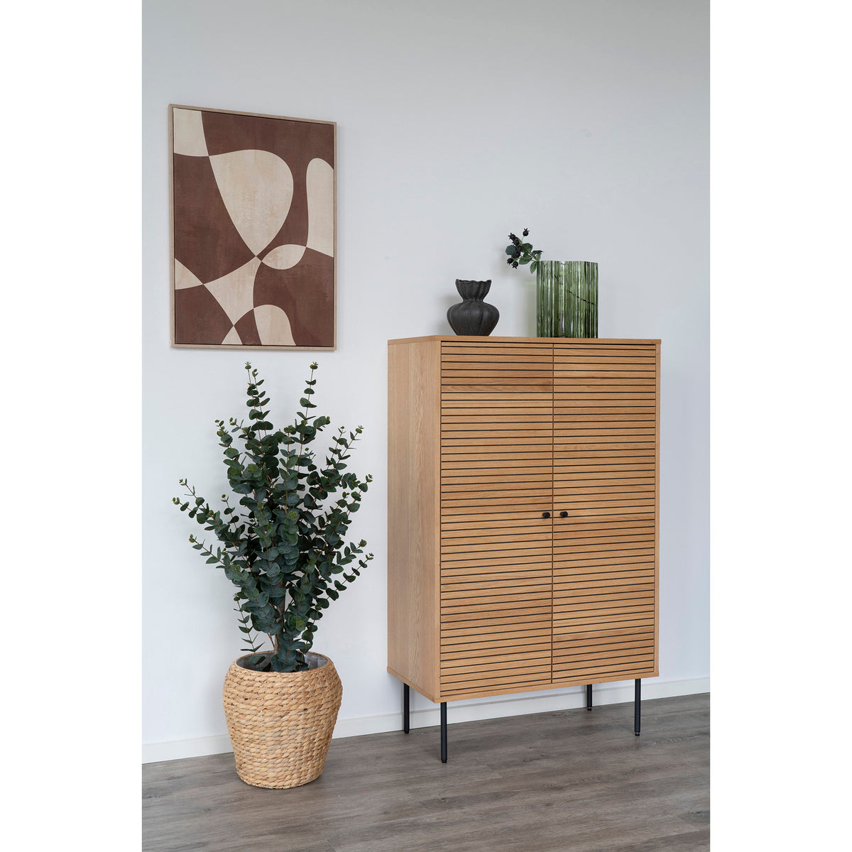 Vase vert fumé strié et vase noir sur un meuble haut en bois clair à lamelles