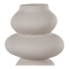 Gros plan sur le col et la surface granuleuse du vase totem en grès beige