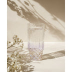 Verre highball irisé rempli d'eau pétillante près d'un bouquet de gypsophile blanche