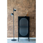 Vitrine Adelaide noire en situation salon mur liège lampadaire noir