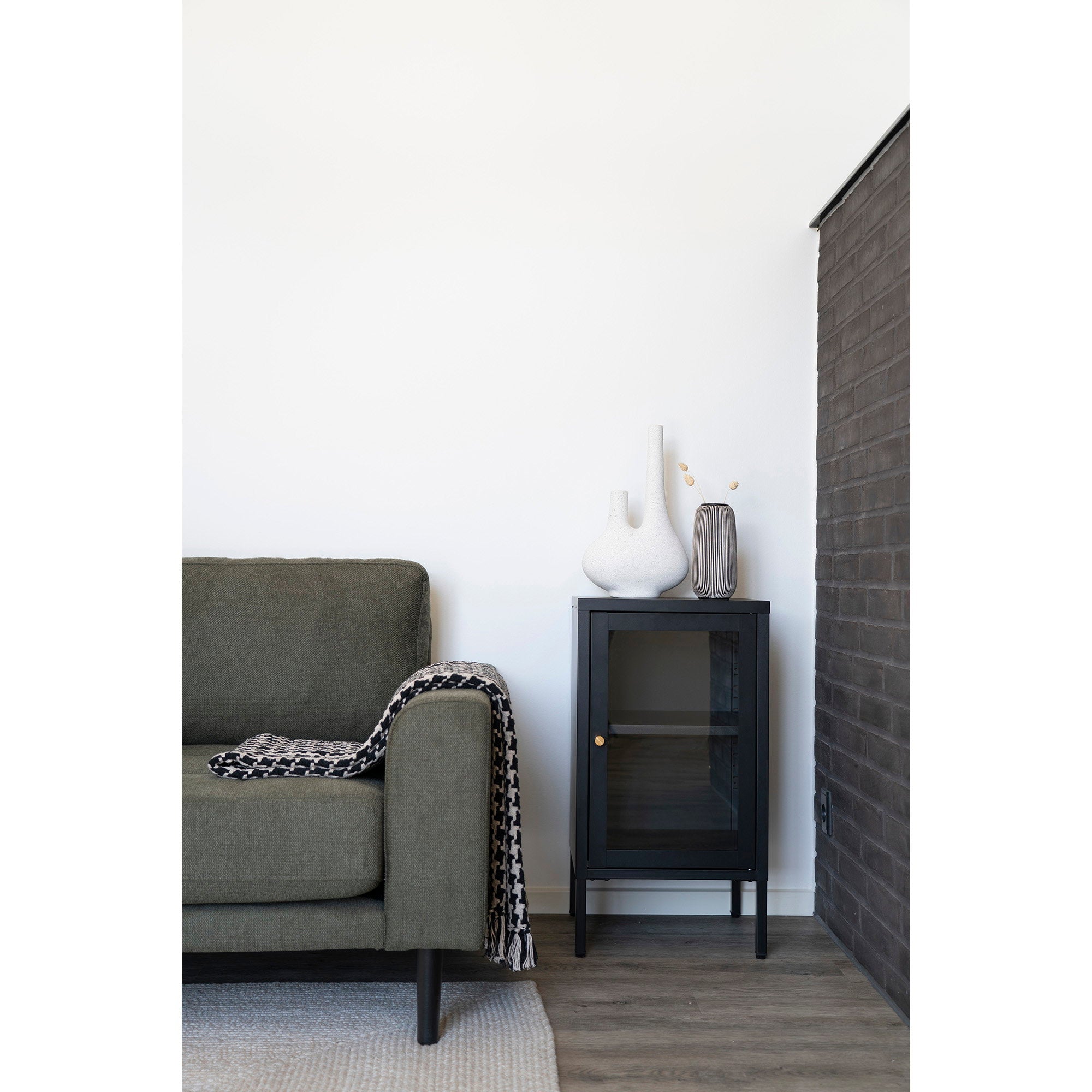 Vitrine Dalby noire en situation salon canapé vert vases décoratifs