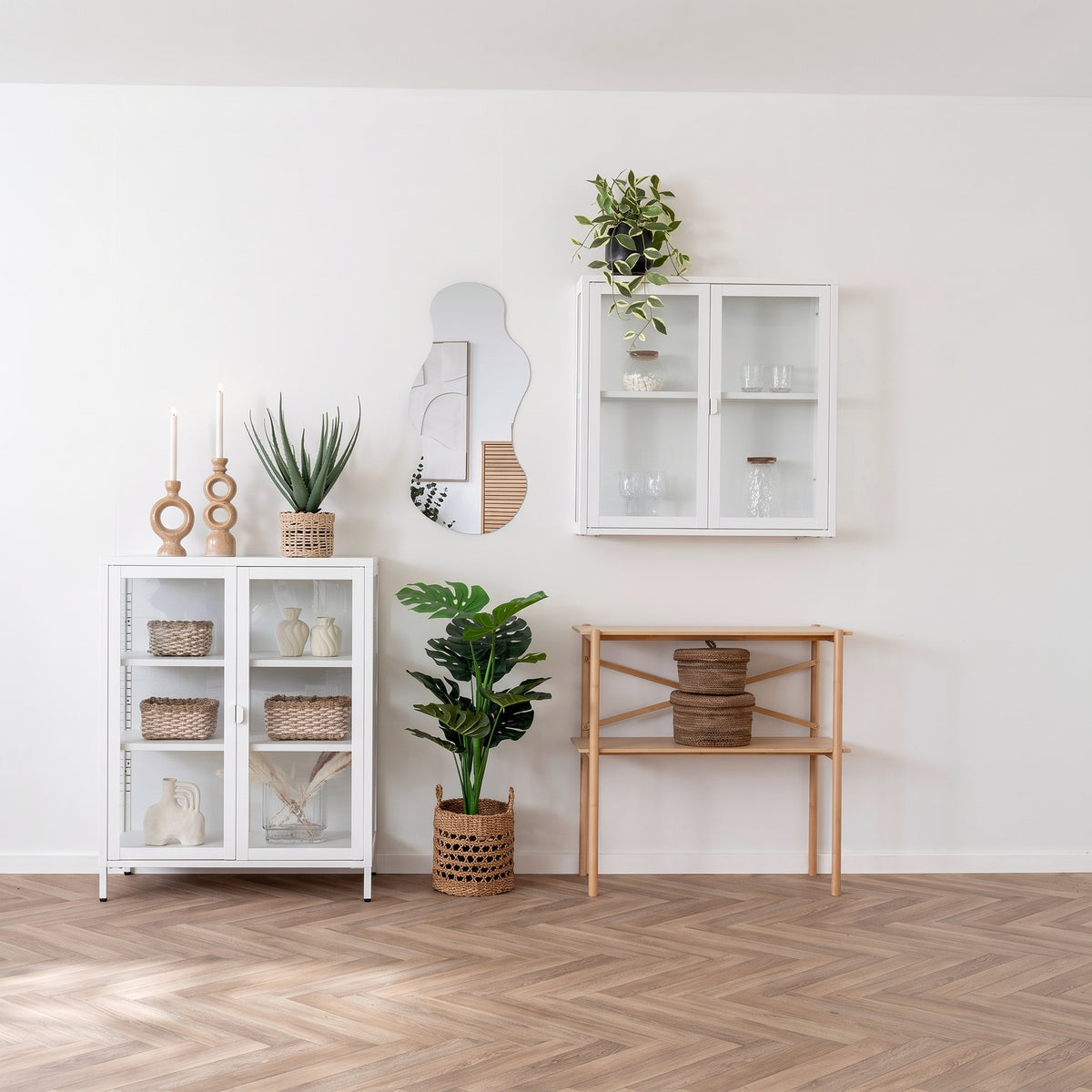 Vitrine murale Brisbane en métal blanc dans un salon au parquet en chevrons, au-dessus d'une console en bois